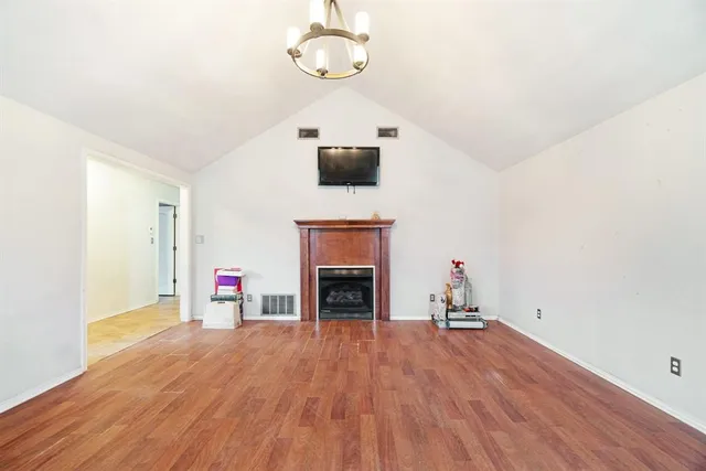 an empty room with wooden floor fireplace and windows