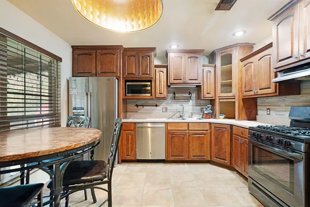 a kitchen with stainless steel appliances granite countertop a stove top oven a sink dishwasher a dining table and chairs with wooden floor
