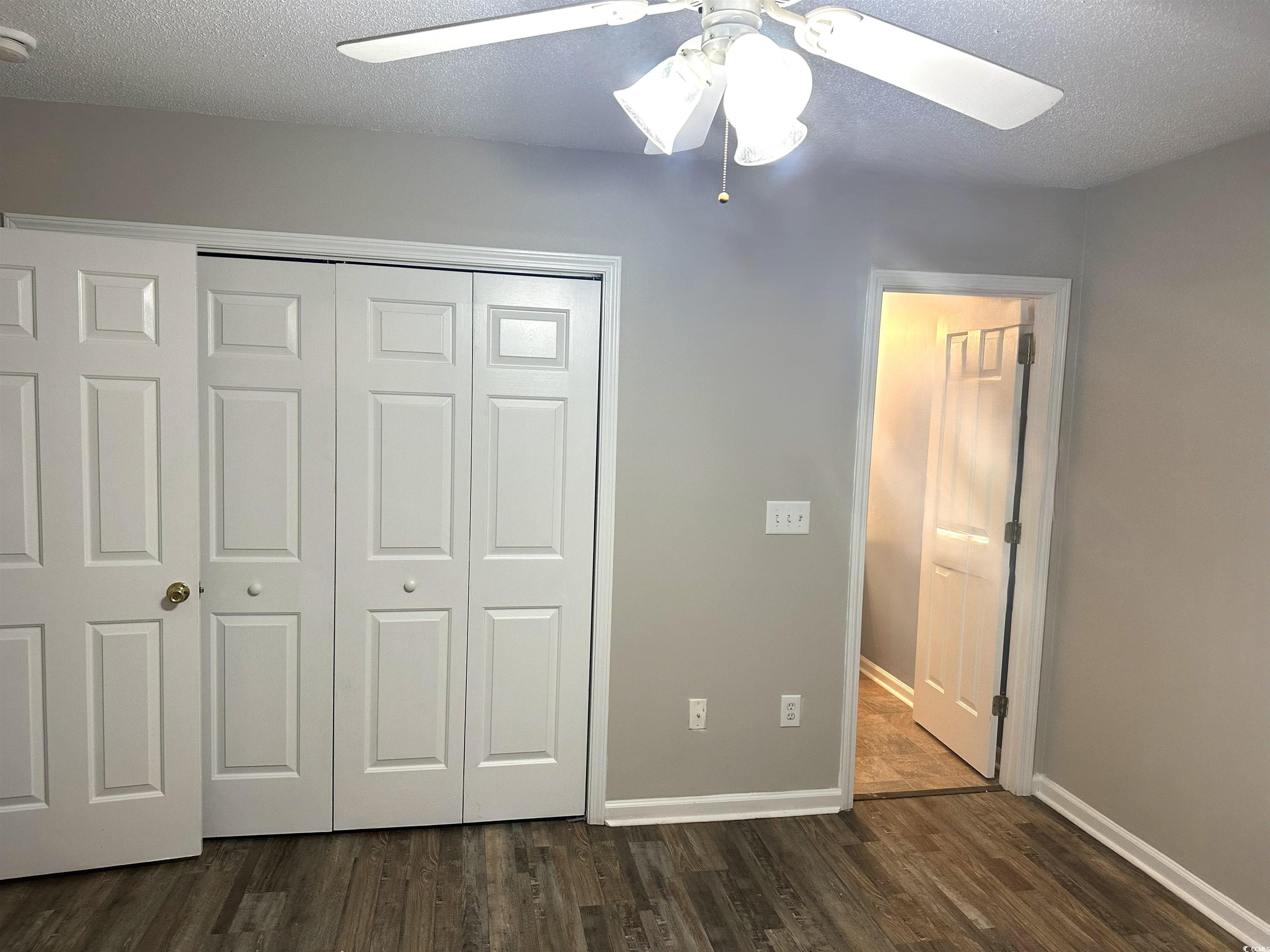 178 Beaver Pond Loop, Unit 60 Pawleys Island, SC 29585 - Photo 19 of 21 Spare room featuring dark wood-style flooring, a ceiling fan, and a textured ceiling