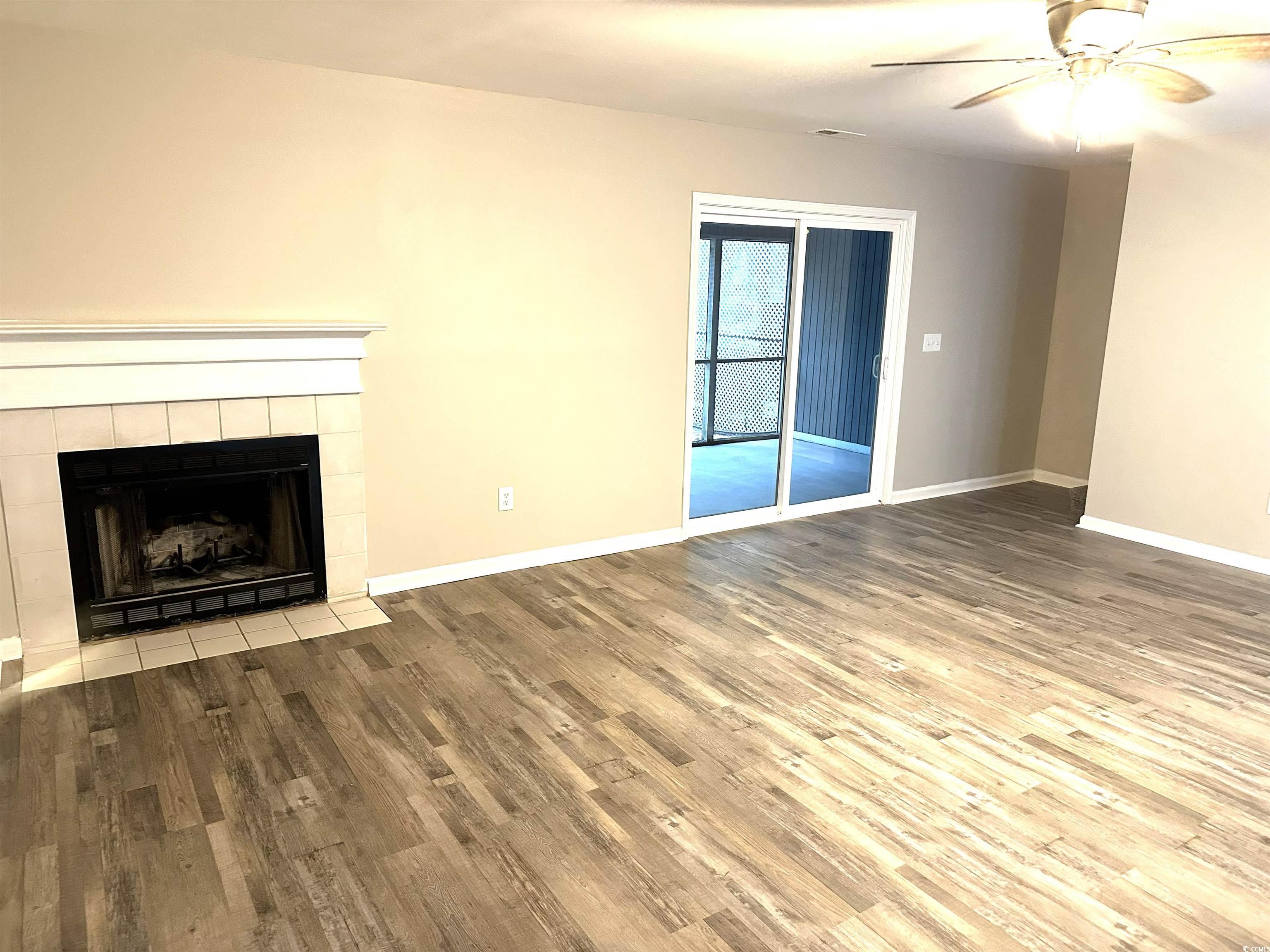 178 Beaver Pond Loop, Unit 60 Pawleys Island, SC 29585 - Photo 4 of 21 Unfurnished living room featuring wood finished floors, a tile fireplace, and a ceiling fan