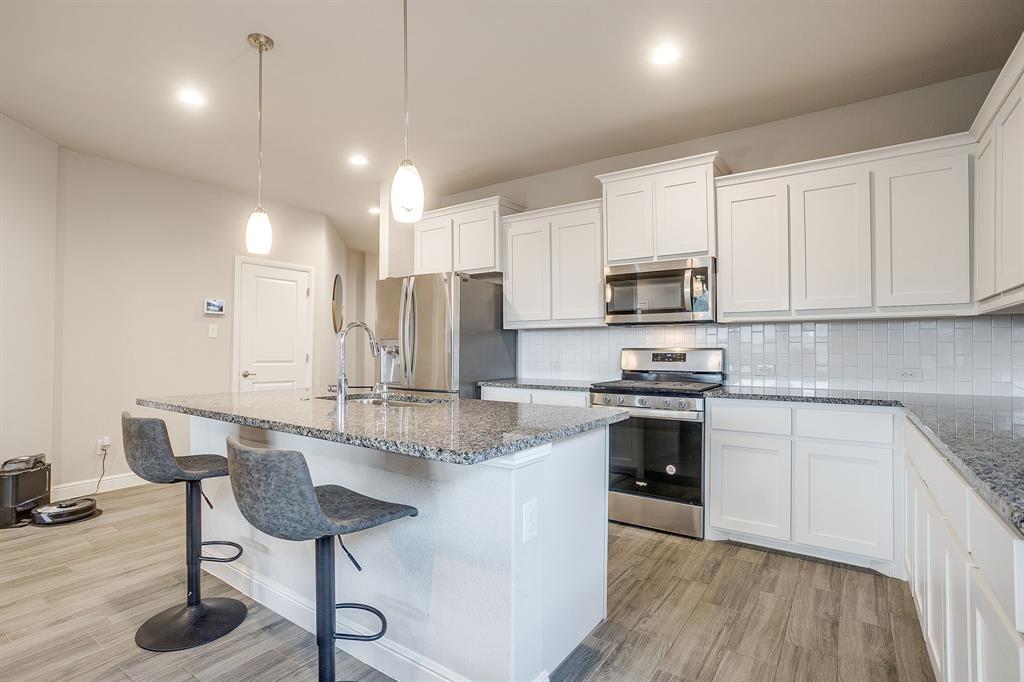 2361 Waggoner Rnch Drive Weatherford, TX 76087 - Photo 5 of 19 a kitchen with kitchen island granite countertop a stove a sink a refrigerator and chairs with wooden floor
