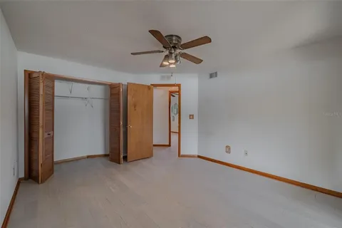 an empty room with wooden floor chandelier and windows