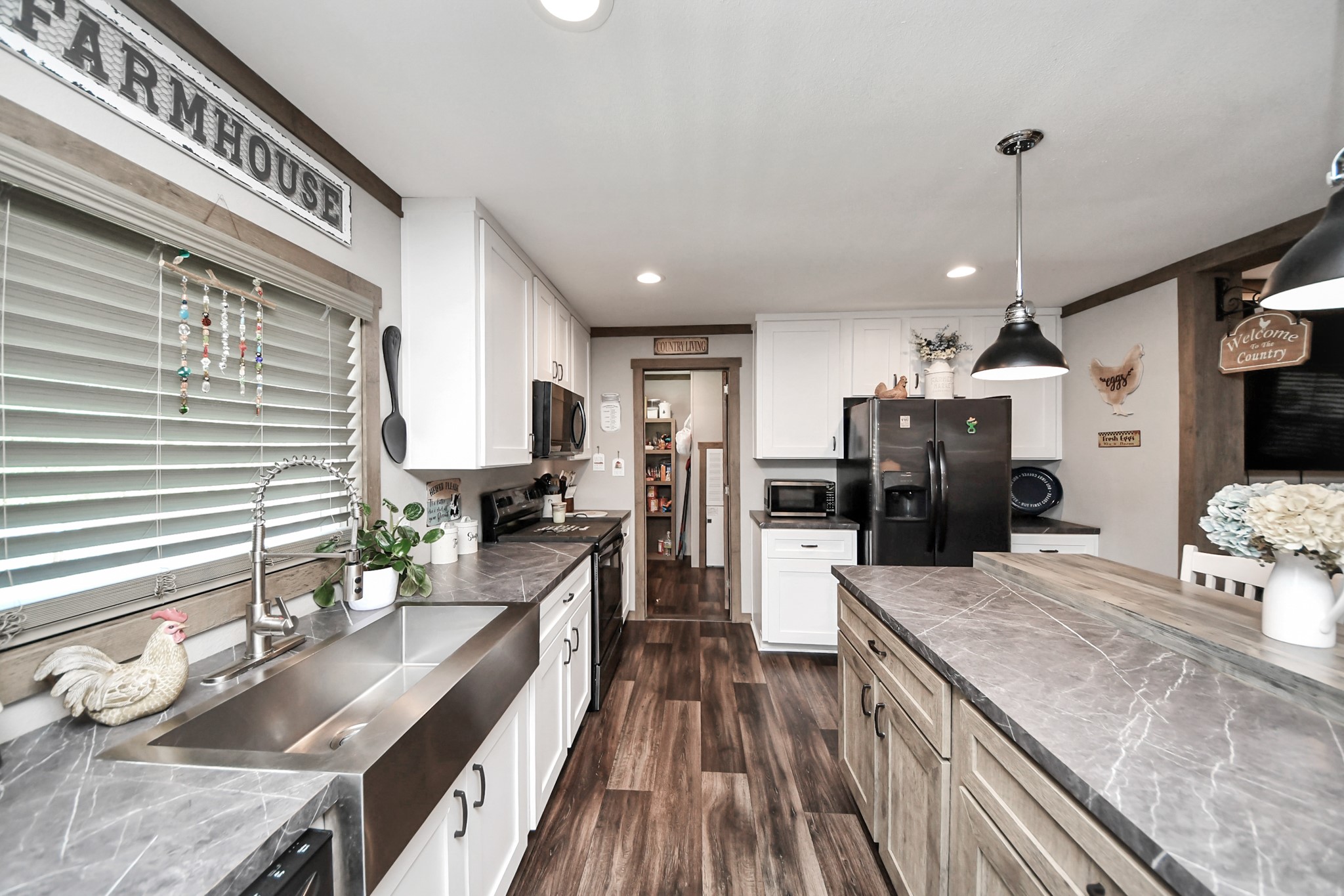 131 Kiowa Court Rosharon, TX 77583 - Photo 5 of 42 This kitchen features a charming farmhouse style with modern amenities. It includes a large farmhouse sink, stainless steel appliances, and ample counter space for cooking. The space is well-lit and showcases rustic vinyl flooring, white cabinets, and cozy atmosphere. Perfect for both cooking and entertaining.