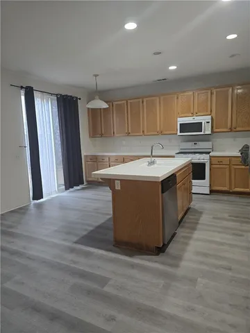 a kitchen with stainless steel appliances granite countertop a stove top oven a sink dishwasher and a refrigerator with wooden floor