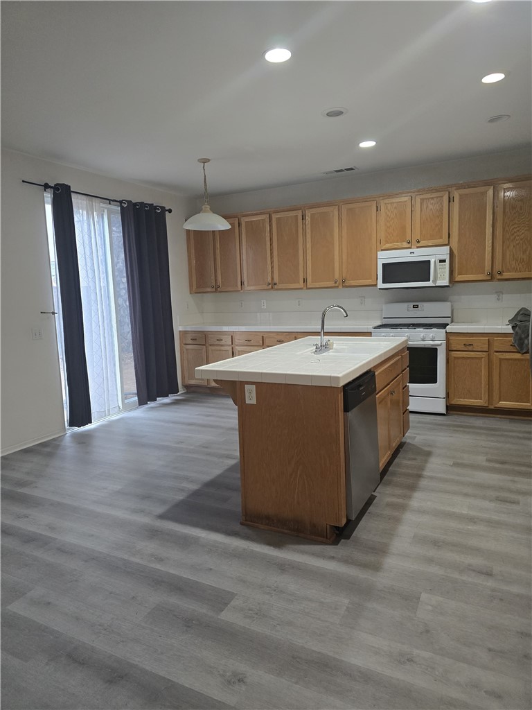 42165 Calabria Drive Temecula, CA 92591 - Photo 6 of 10 a kitchen with stainless steel appliances granite countertop a stove top oven a sink dishwasher and a refrigerator with wooden floor