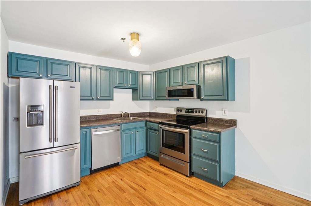 890 Glendale Terrace Northeast, Unit 1 Atlanta, GA 30309 - Photo 8 of 19 a kitchen with stainless steel appliances granite countertop a refrigerator stove a sink dishwasher and microwave with wooden floor