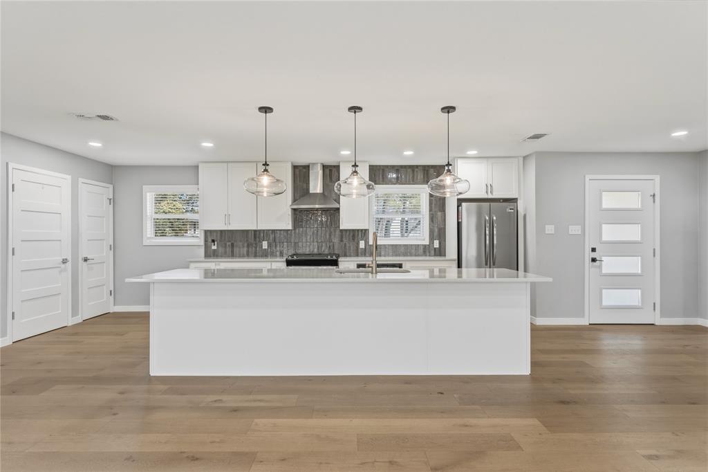 a large white kitchen with wooden floors