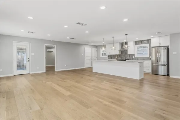 a view of a kitchen with stainless steel appliances refrigerator a microwave and white cabinets