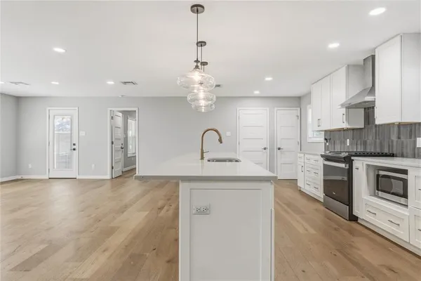 a large kitchen with kitchen island white cabinets and stainless steel appliances