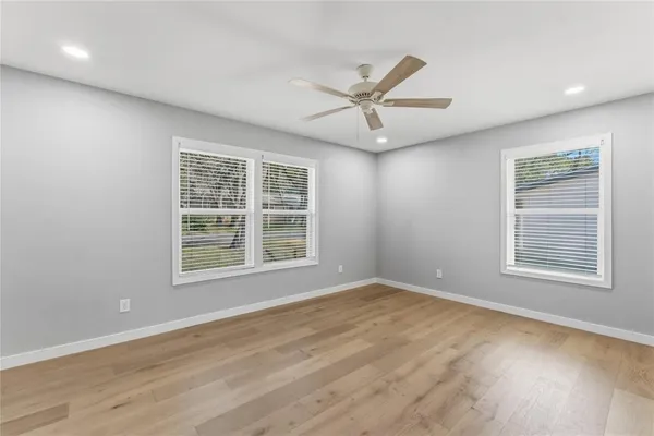 a view of empty room with wooden floor and ceiling fan