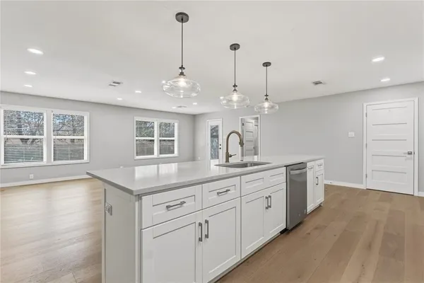a view of a kitchen with kitchen island a sink wooden floor and floors