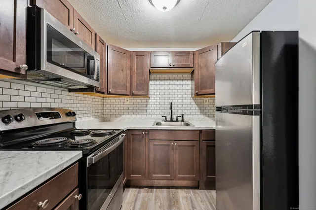 a kitchen with stainless steel appliances granite countertop a sink stove and refrigerator