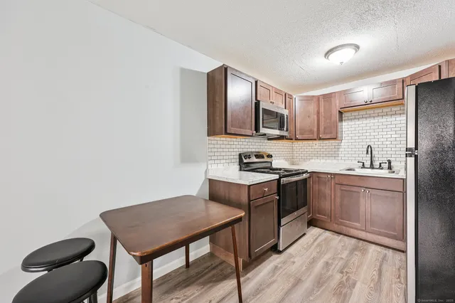 a kitchen with stainless steel appliances a stove top oven a sink dishwasher and microwave with wooden floor
