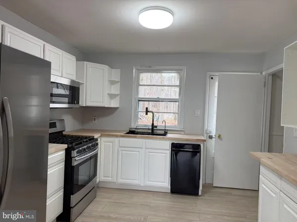 a kitchen with stainless steel appliances granite countertop white cabinets a sink a stove a refrigerator and a microwave
