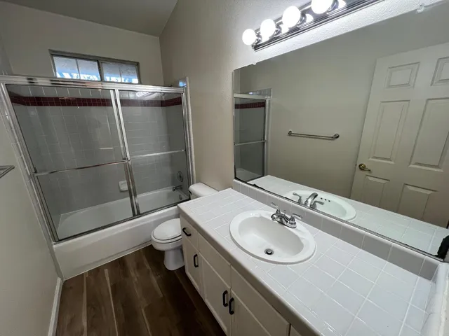 a bathroom with a sink a toilet a mirror and shower