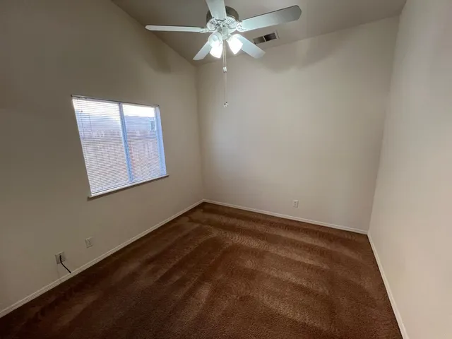 an empty room with a window and a fan