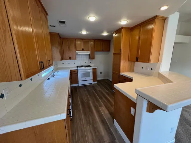 a large kitchen with stainless steel appliances a large counter top a stove and a refrigerator