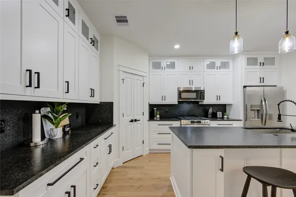 a kitchen with stainless steel appliances granite countertop a sink a stove and a refrigerator