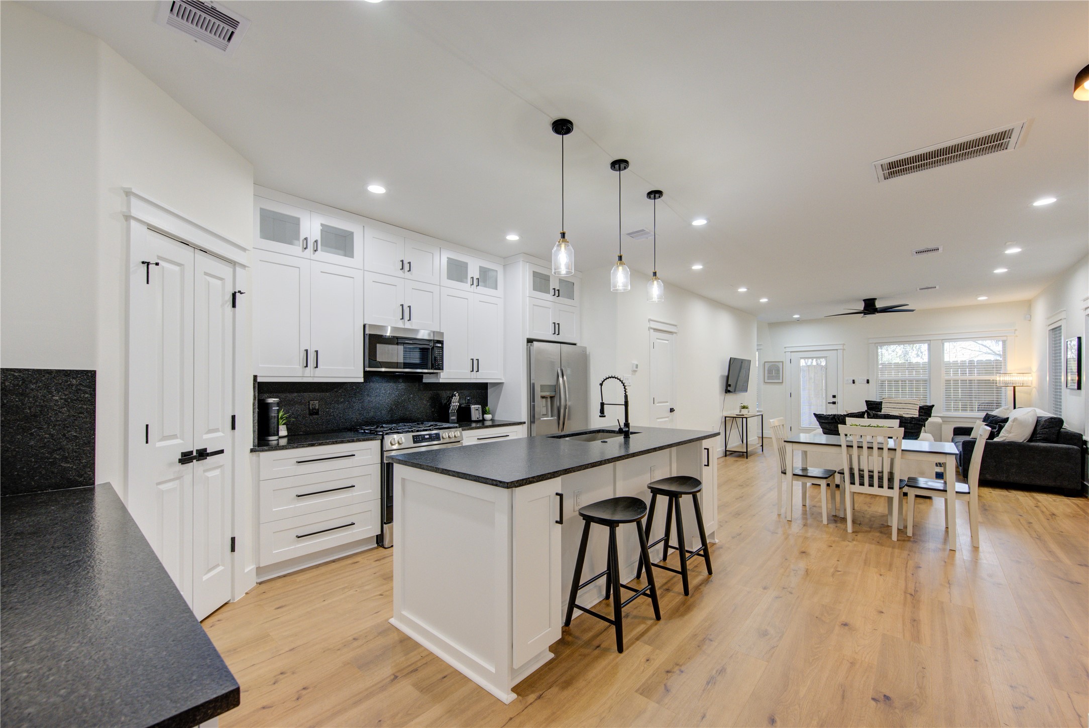 3406 Garapan Street, Unit A Houston, TX 77091 - Photo 13 of 44 a kitchen with stainless steel appliances kitchen island granite countertop a stove a sink a refrigerator and a dining table with wooden floor