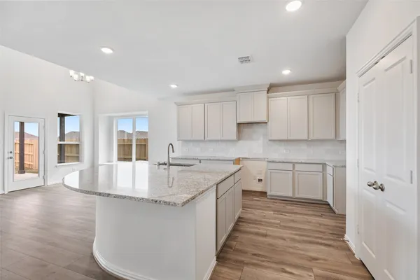 a kitchen with a sink dishwasher a stove and white cabinets with wooden floor