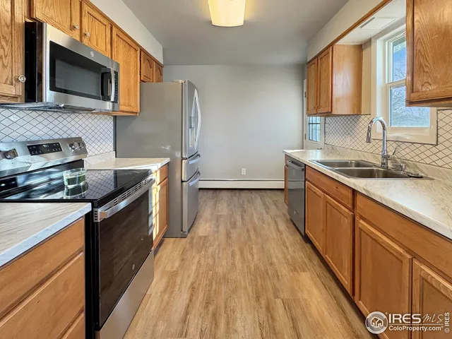 a kitchen with stainless steel appliances granite countertop a stove a sink dishwasher and a microwave oven with wooden floor