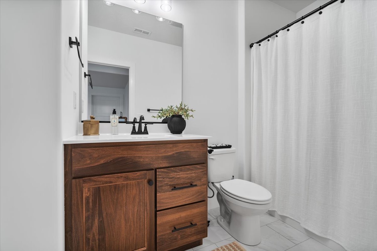 5305 Finlen Lane Bloomington, IL 61705 - Photo 38 of 42 a bathroom with a sink a toilet a mirror and shower curtain