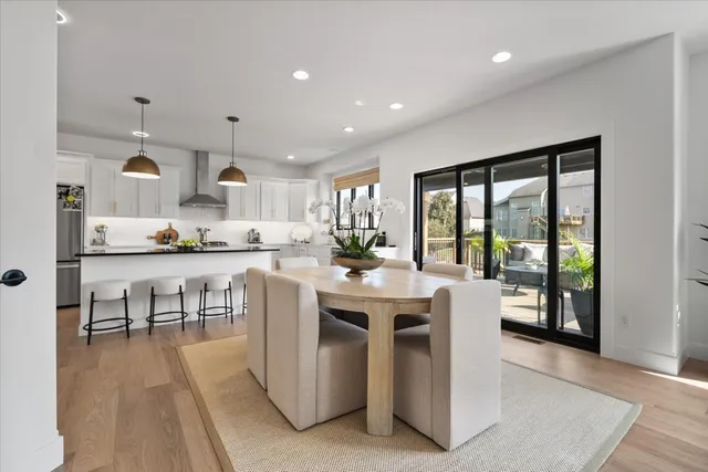 a kitchen with stainless steel appliances granite countertop a stove top oven a sink a dining table and chairs