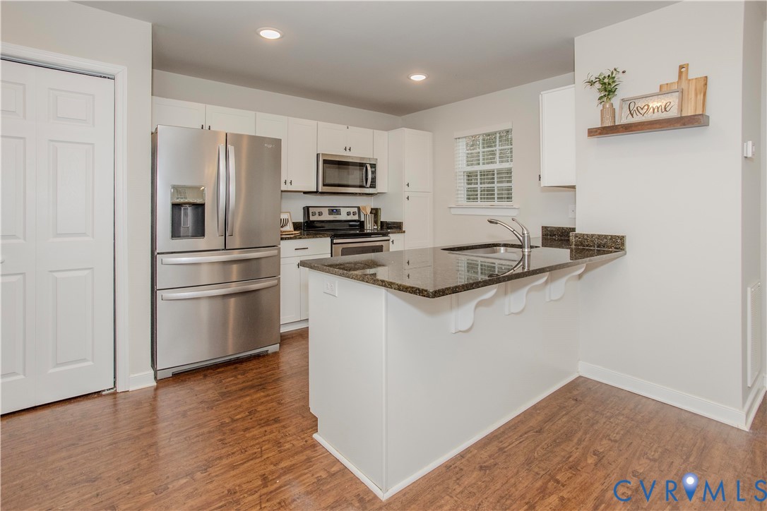 1561 Burning Tree Road Henrico, VA 23231 - Photo 5 of 29 a kitchen with stainless steel appliances granite countertop a refrigerator a stove a sink a microwave oven with white cabinets and wooden floor