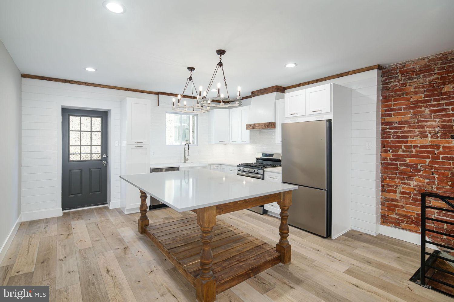 a room with stainless steel appliances a dining table wooden floor and a refrigerator