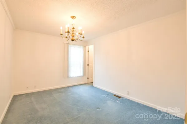 an empty room with a chandelier fan and windows