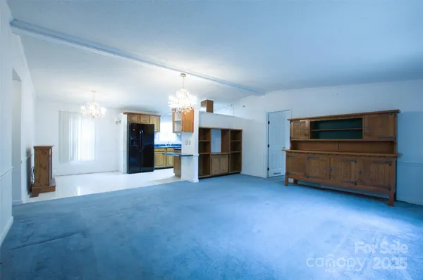 a view of an empty room with kitchen and a window