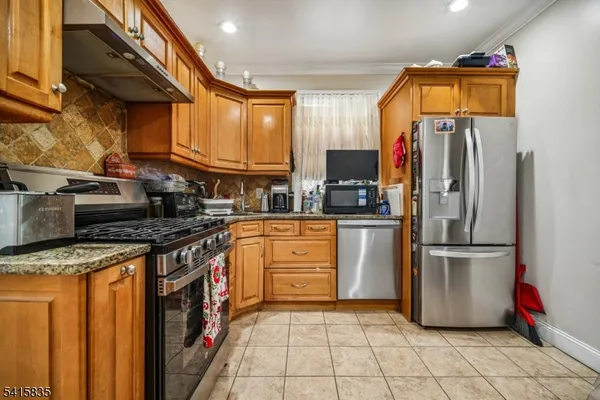 a kitchen with stainless steel appliances granite countertop a refrigerator a stove and a sink