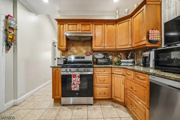 a kitchen with stainless steel appliances granite countertop a stove a sink and a microwave