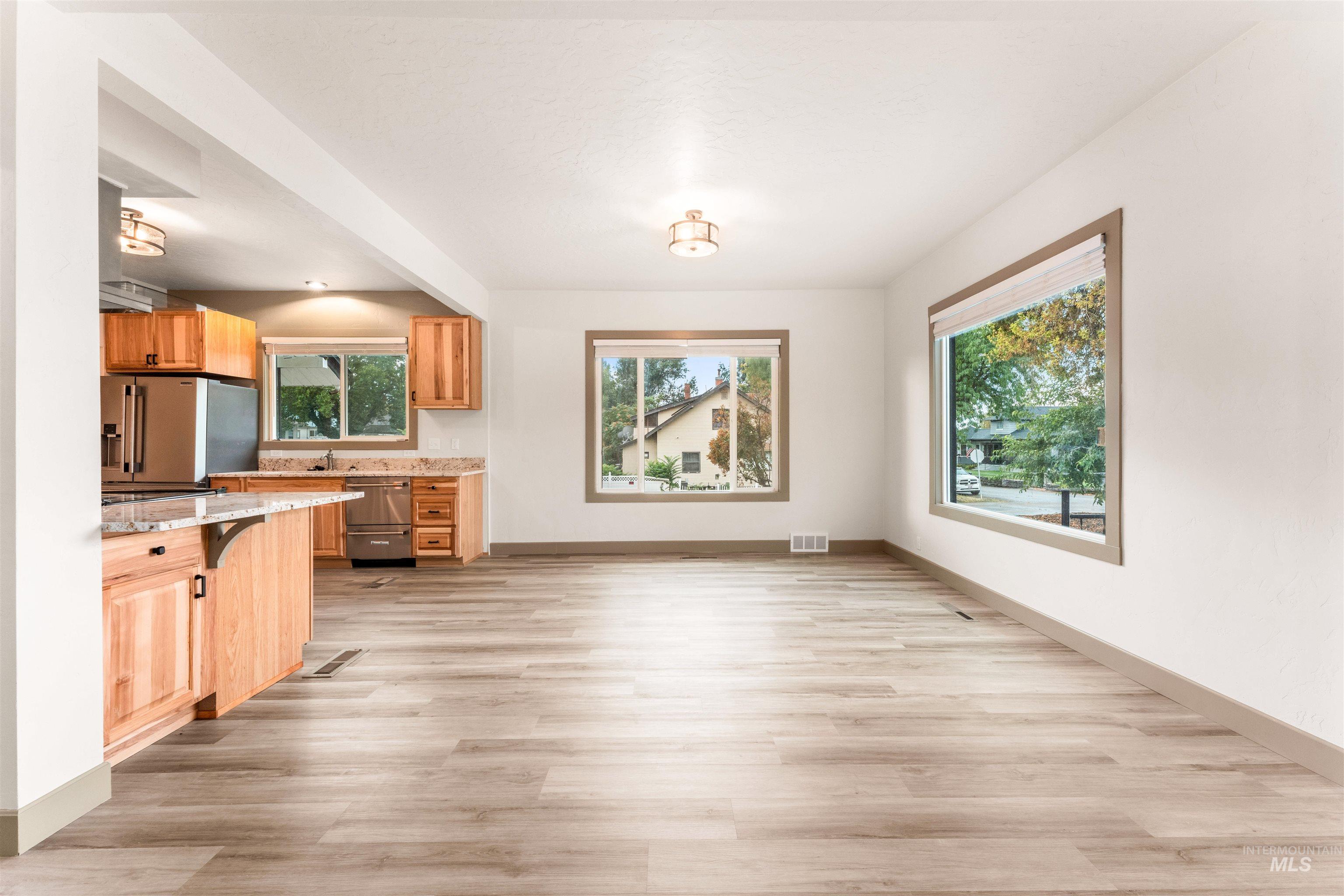 602 North 5th Street Parma, ID 83660 - Photo 15 of 48 Kitchen with light stone counters, light wood-style flooring, appliances with stainless steel finishes, and a kitchen bar