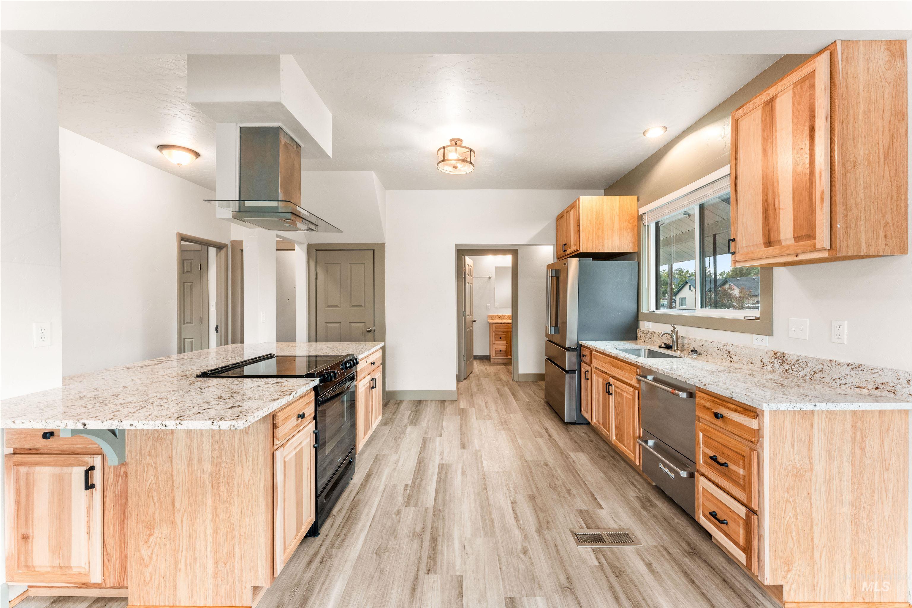 602 North 5th Street Parma, ID 83660 - Photo 17 of 48 Kitchen with light brown cabinets, light stone counters, stainless steel appliances, light wood-style flooring, and island exhaust hood