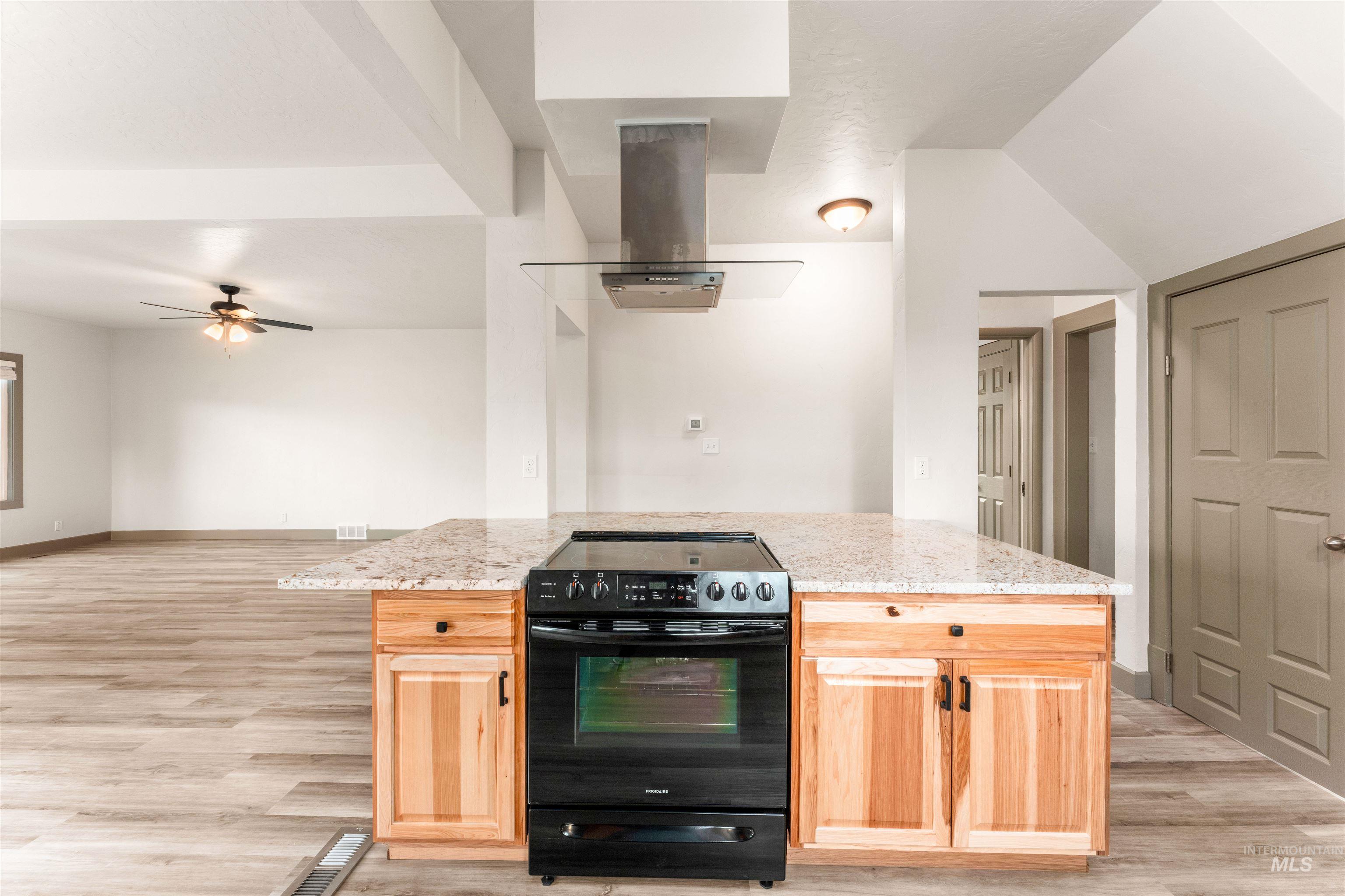 602 North 5th Street Parma, ID 83660 - Photo 19 of 48 Kitchen with a kitchen island, black electric range, light brown cabinets, island range hood, and light wood-style flooring
