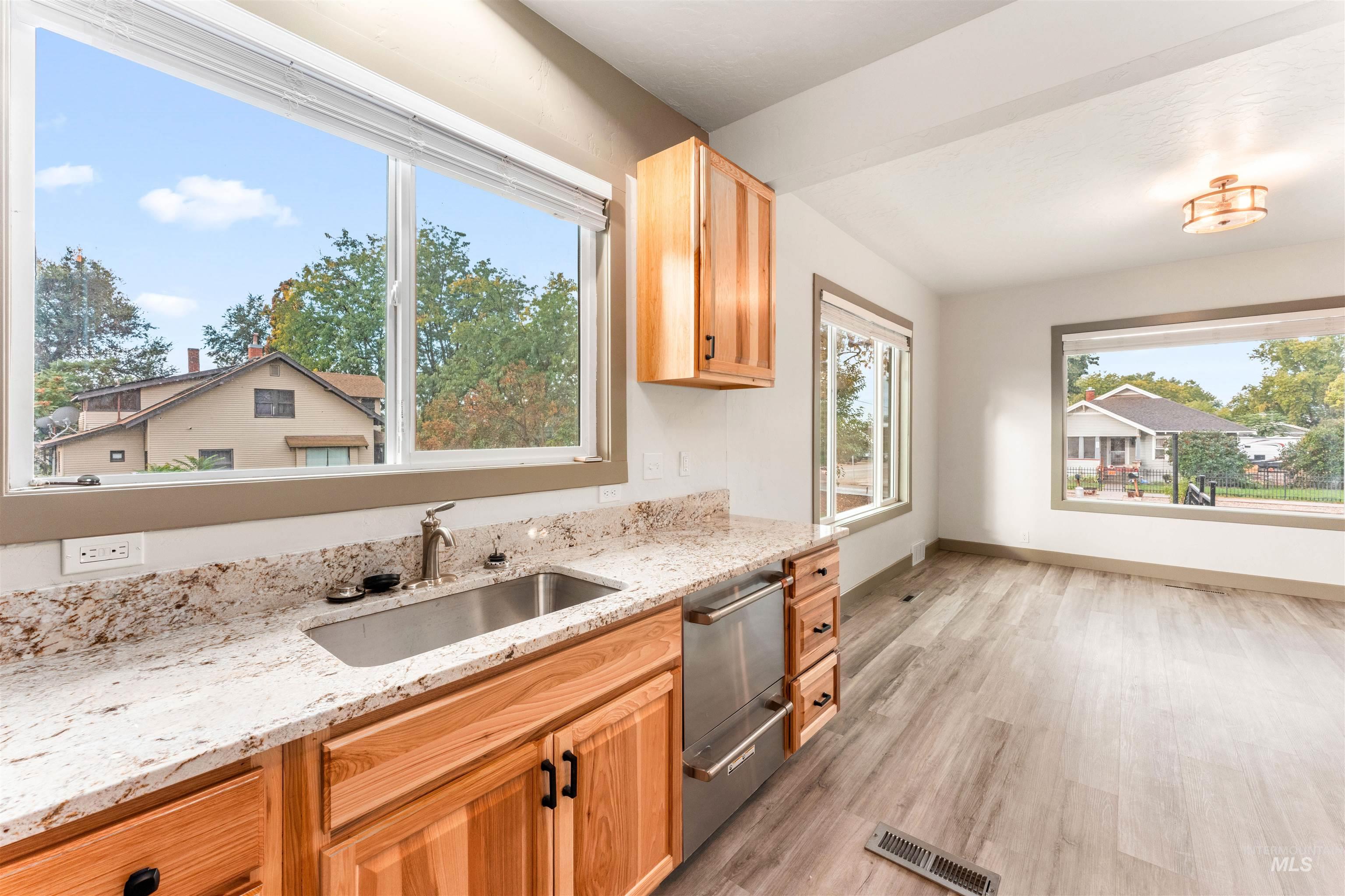 602 North 5th Street Parma, ID 83660 - Photo 20 of 48 Kitchen featuring light wood-style floors, light stone countertops, stainless steel dishwasher, and light brown cabinetry