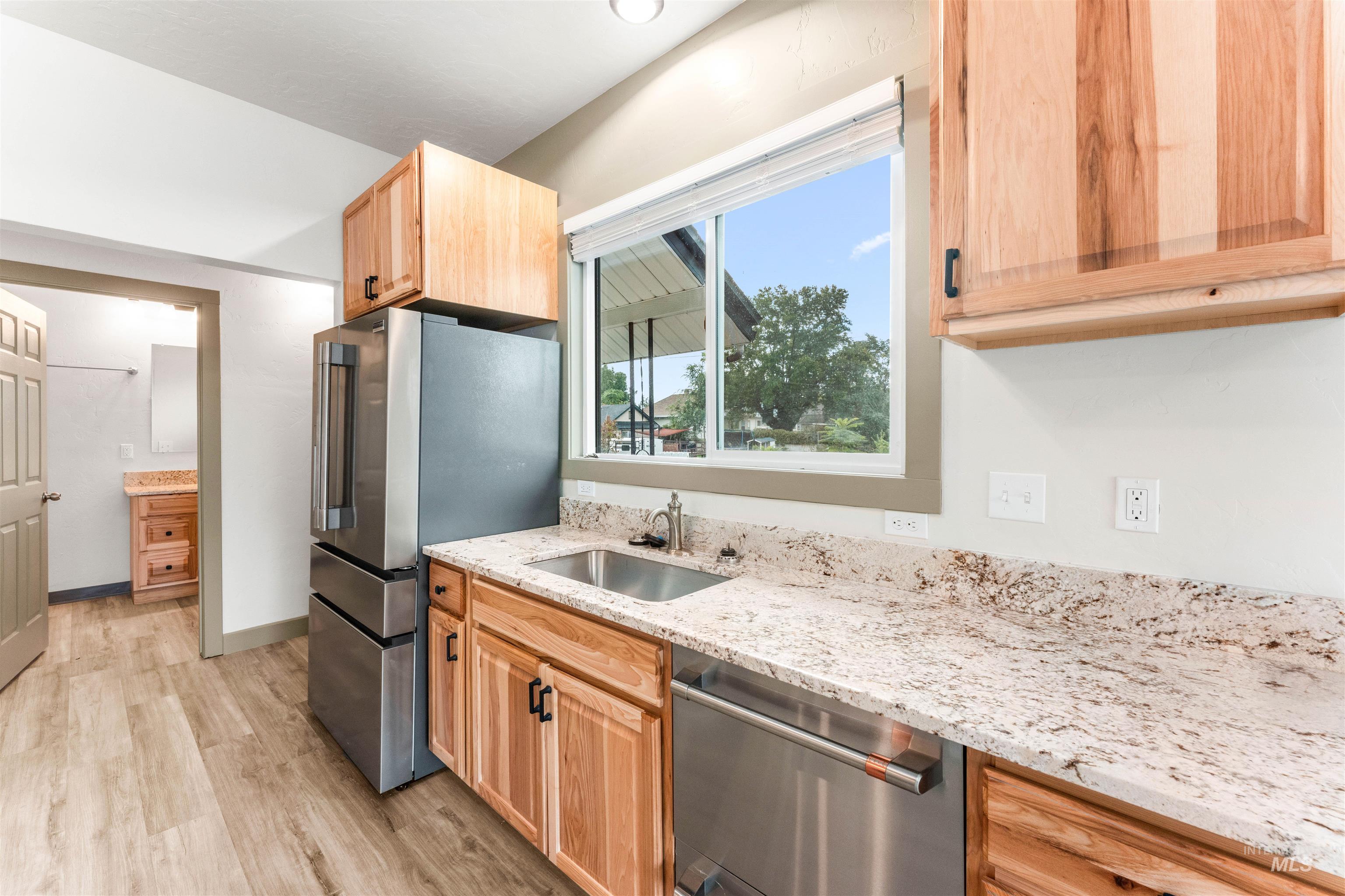 602 North 5th Street Parma, ID 83660 - Photo 21 of 48 Kitchen with light stone counters, appliances with stainless steel finishes, light wood finished floors, and light brown cabinetry