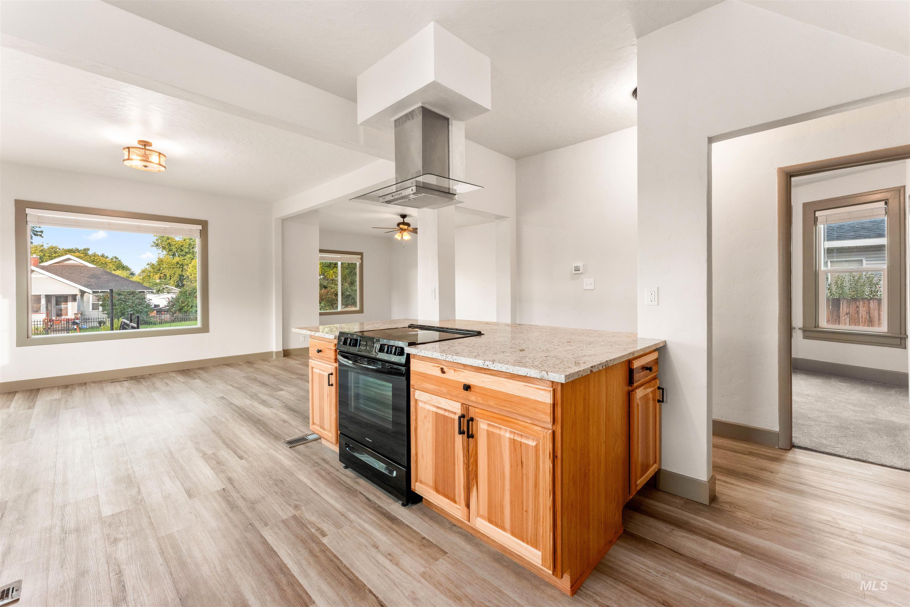 602 North 5th Street Parma, ID 83660 - Photo 22 of 48 Kitchen featuring black electric range, light stone countertops, light wood-type flooring, island exhaust hood, and ceiling fan