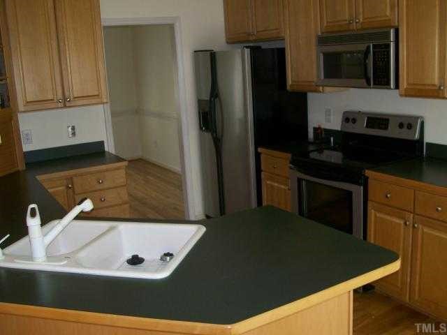 6301 Ashley Ridge Drive Raleigh, NC 27612 - Photo 3 of 12 a kitchen with stainless steel appliances granite countertop a refrigerator a stove and a sink