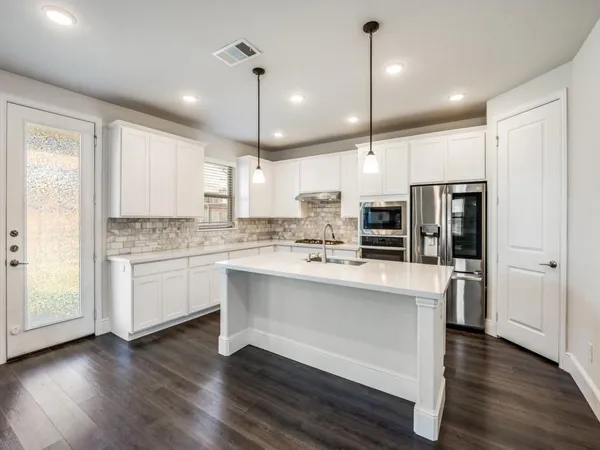 a large kitchen with white cabinets stainless steel appliances a sink and a center island