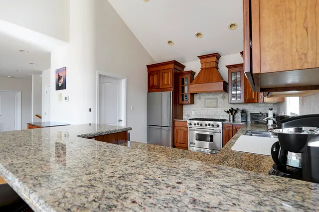a kitchen with stainless steel appliances granite countertop a stove top oven a sink a counter space and cabinets