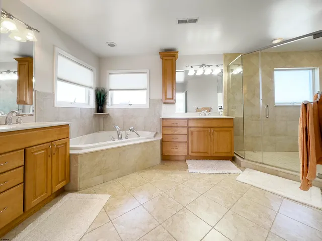 a spacious bathroom with a tub sink shower and mirror
