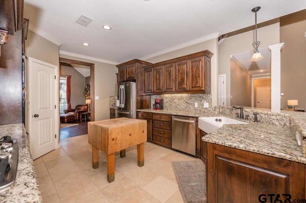 8553 Castleton Way Tyler, TX 75703 - Photo 13 of 38 a large kitchen with kitchen island a large counter space a sink stainless steel appliances and cabinets