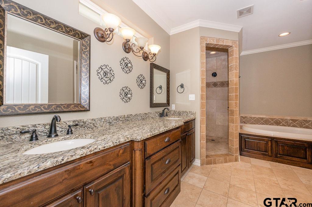 8553 Castleton Way Tyler, TX 75703 - Photo 22 of 38 a bathroom with a granite countertop sink a mirror a vanity and a bathtub