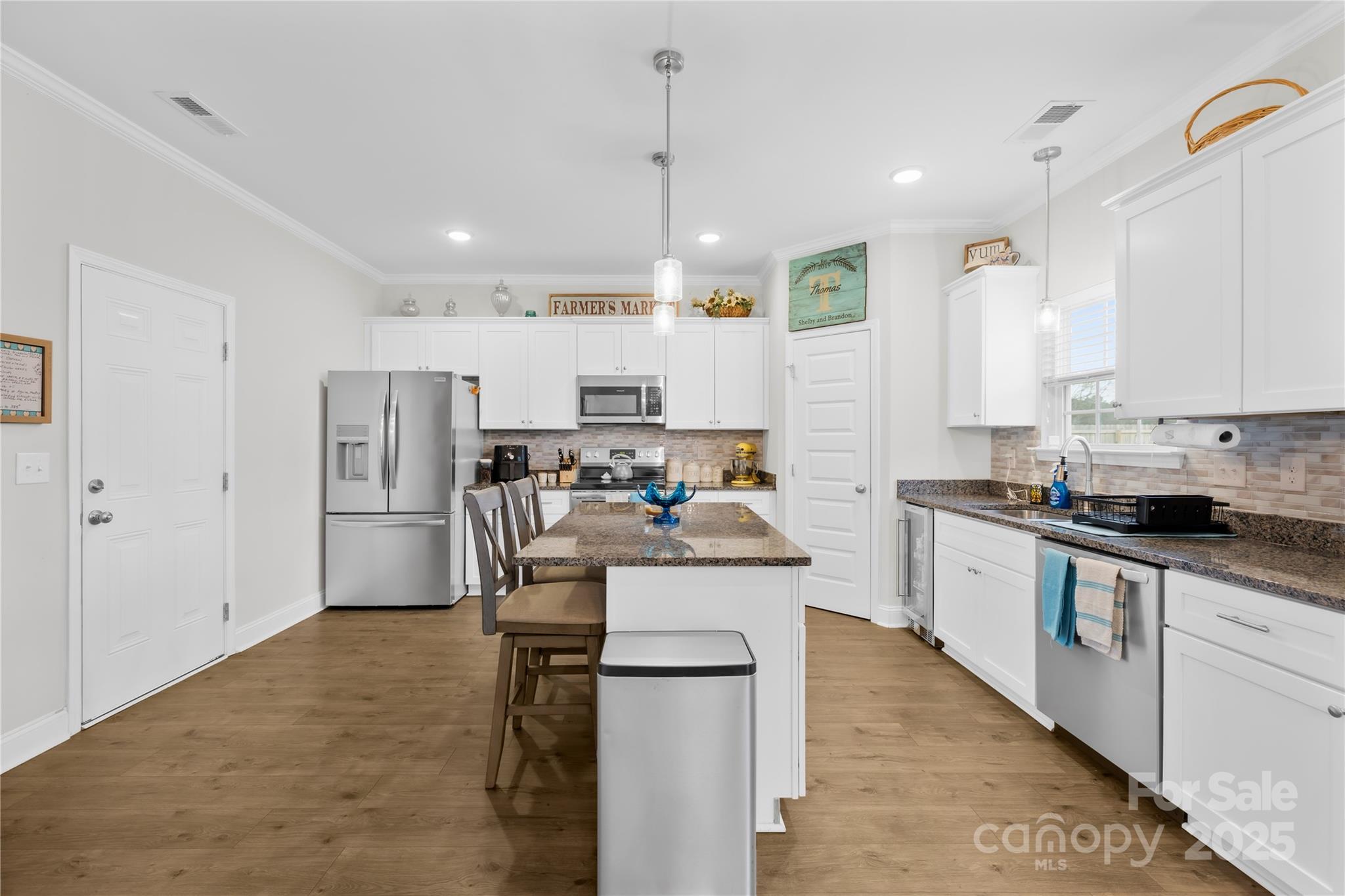 5405 Austin Road Monroe, NC 28112 - Photo 6 of 38 a kitchen with stainless steel appliances kitchen island granite countertop a stove top oven a refrigerator a sink and white cabinets with wooden floor