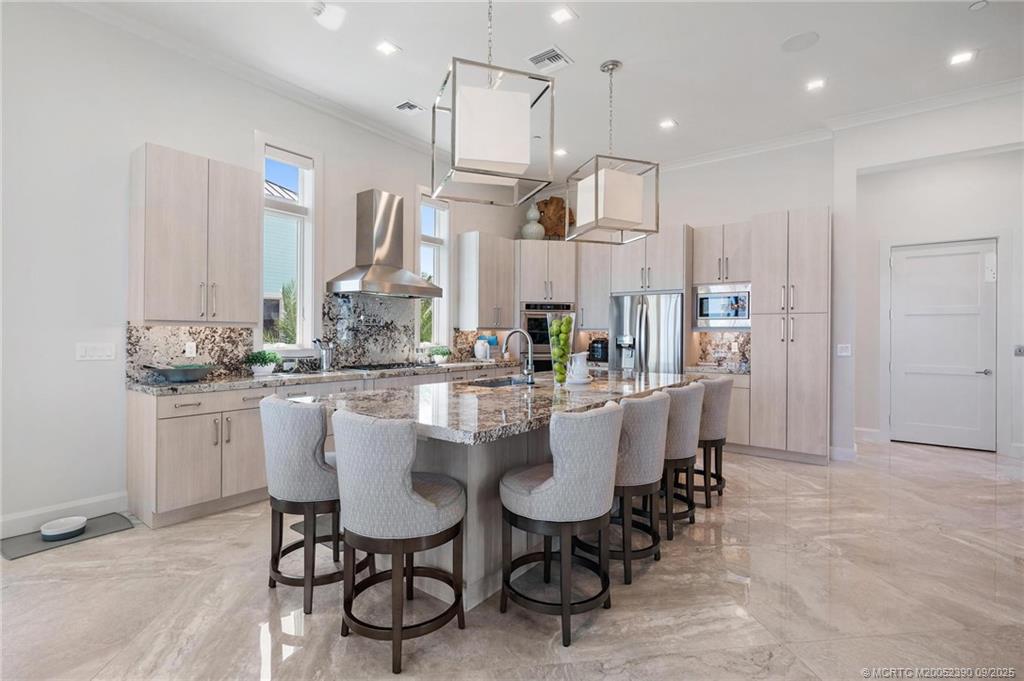 4860 Watersong Way Fort Pierce, FL 34949 - Photo 14 of 45 a kitchen with kitchen island stainless steel appliances a dining table chairs sink and cabinets