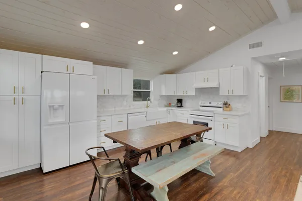 a kitchen with stainless steel appliances granite countertop a table chairs sink and cabinets
