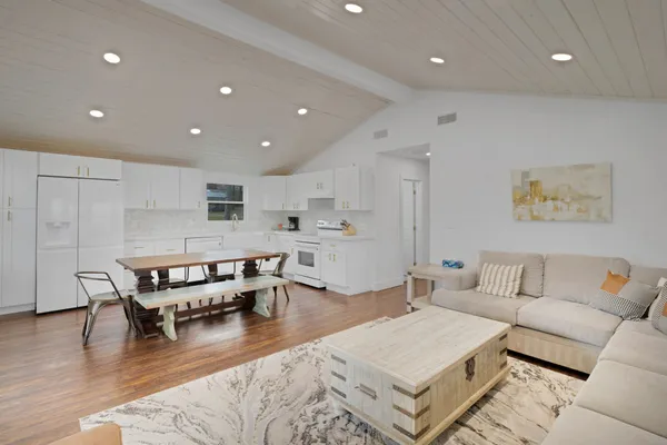 a living room with furniture and kitchen view with wooden floor