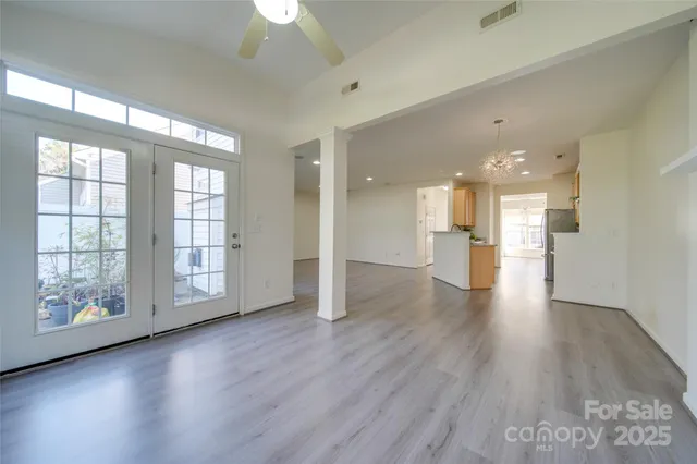 a view of an empty room with wooden floor and a kitchen